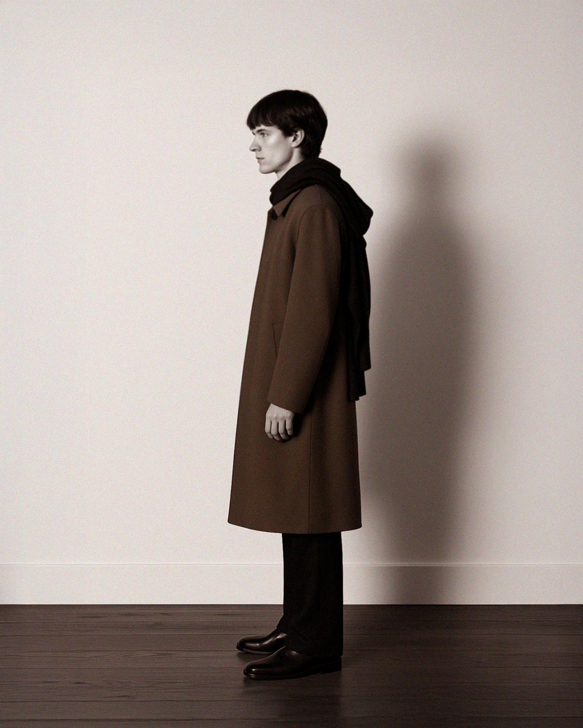Model wearing Casca 222 Luxury Cashmere Brown tailored coat on a white background. Savile Row style. The Row trousers. Margiela Scarf. Prada shoes.