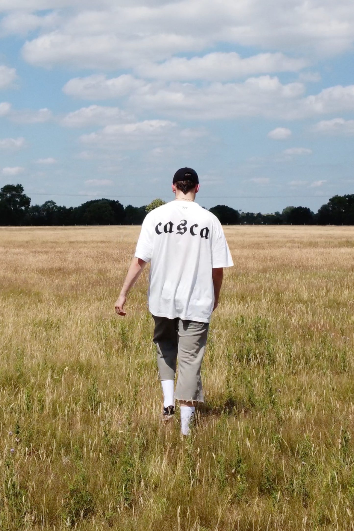 Model wearing oversized off-white t-shirt with casca printed logo onback, 222 distressed cap, faded sweatpants. enfant riches deprimes, ERD, vintage, balenciaga, chrome hearts
