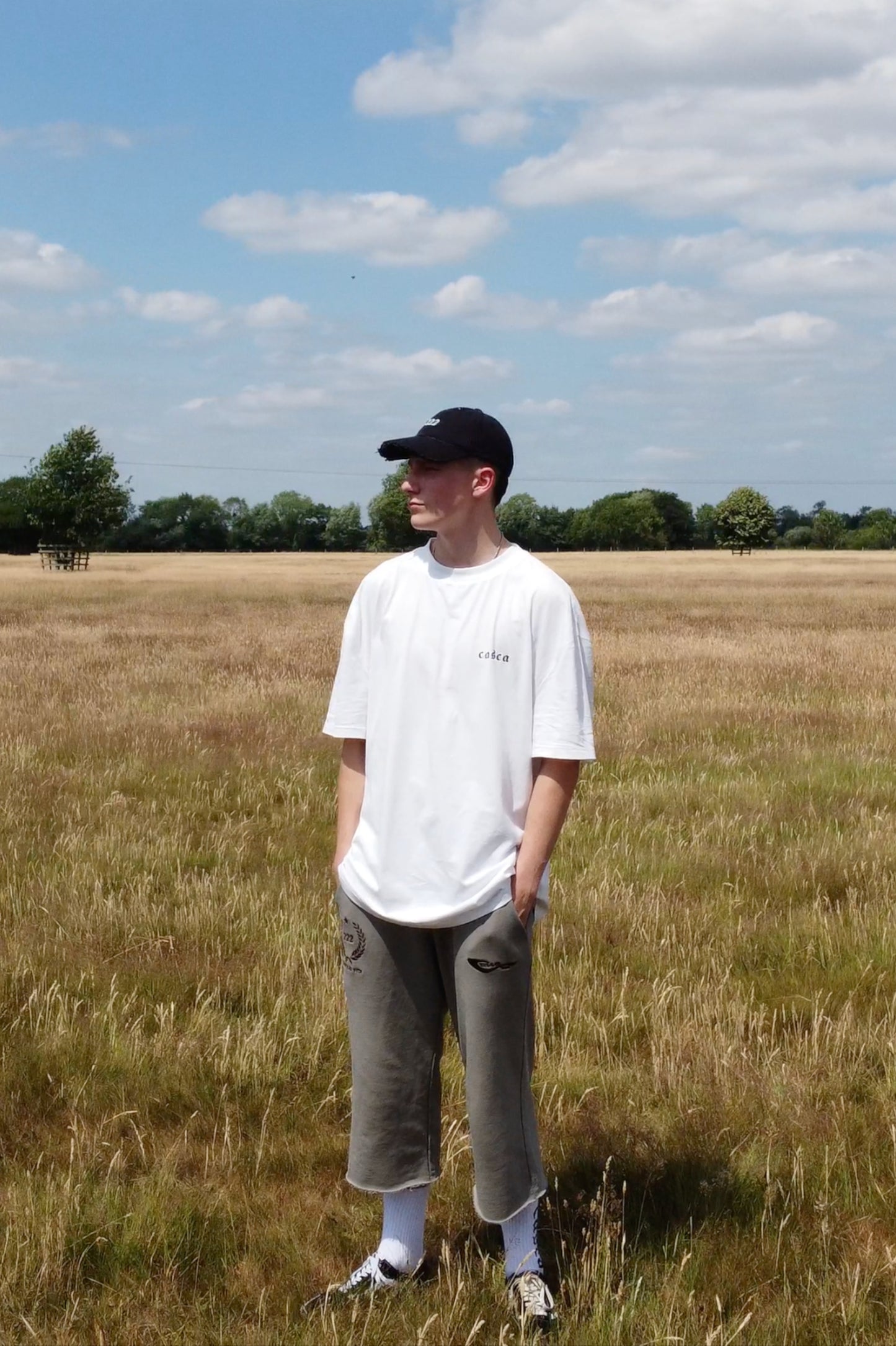 Model wearing oversized off-white t-shirt with casca printed logo on front, 222 distressed cap, faded sweatpants. enfant riches deprimes, ERD, vintage, balenciaga, chrome hearts