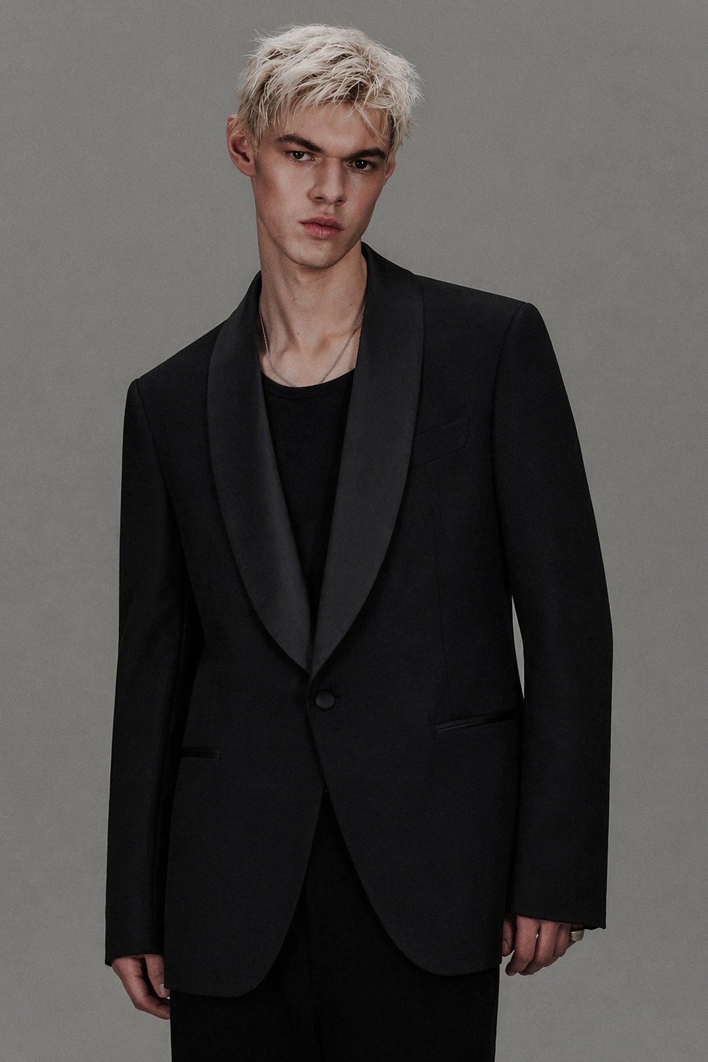 Man wearing a black tuxedo against a gray background
