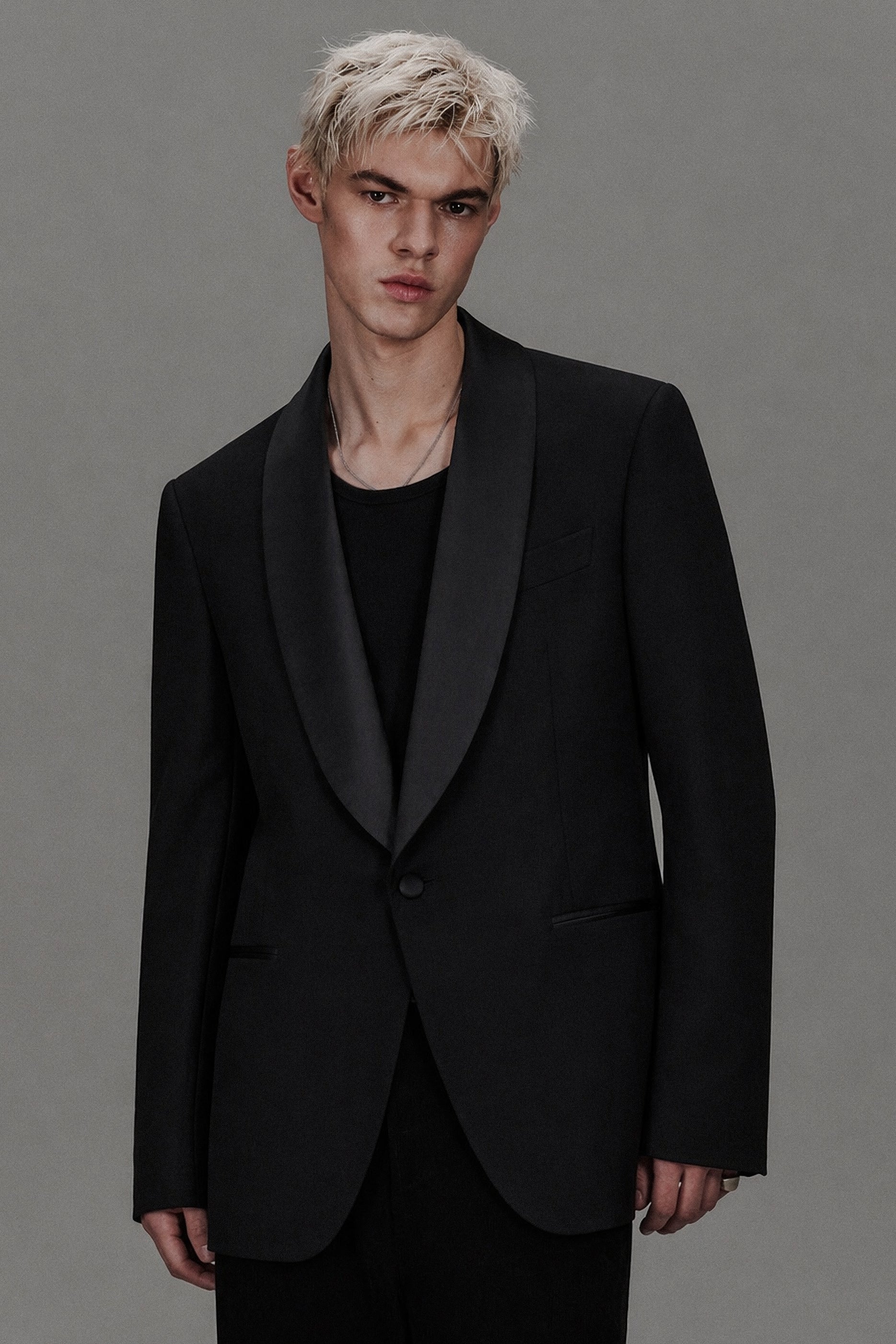 Man wearing a black tuxedo against a gray background