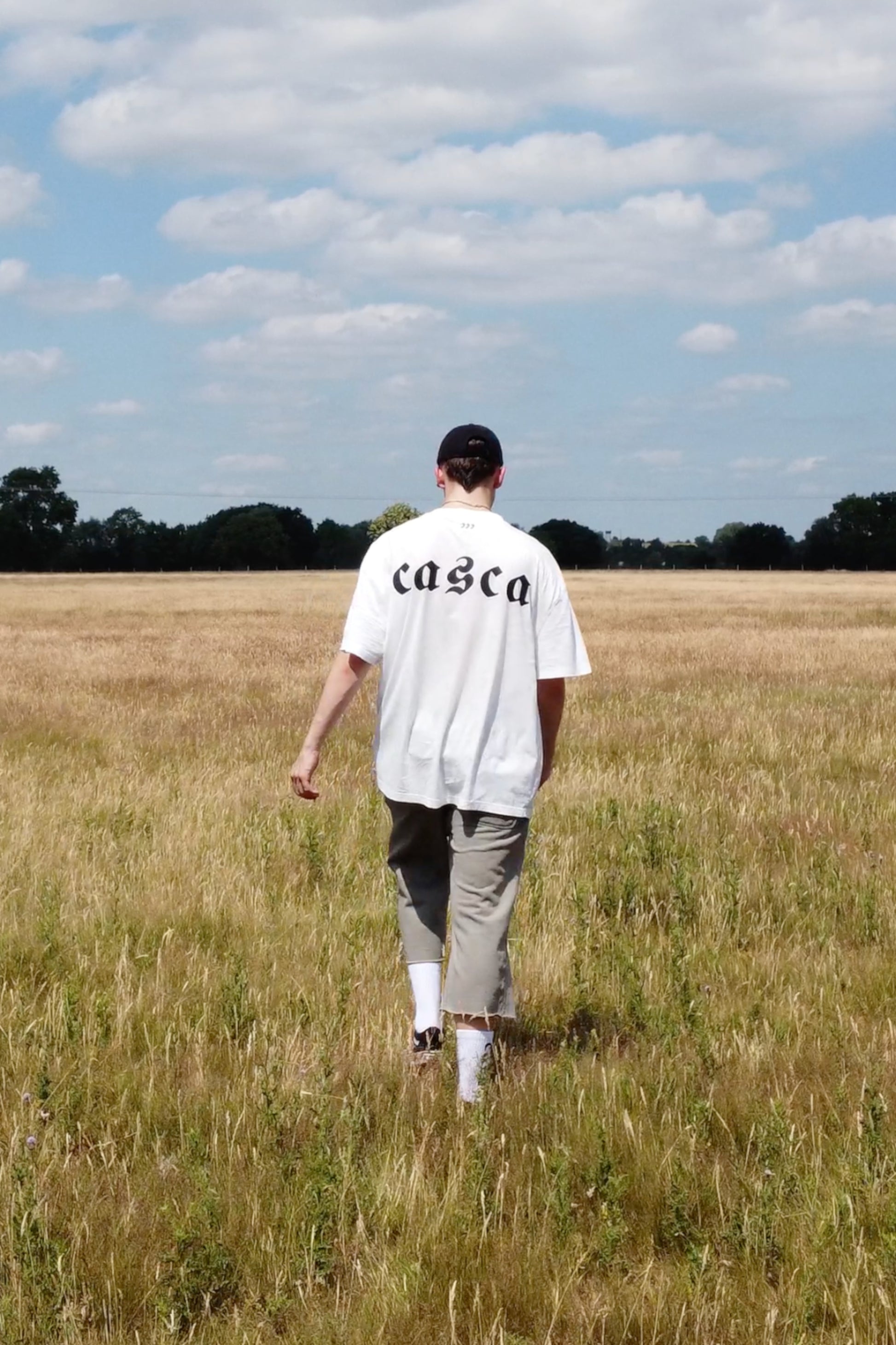 Model wearing oversized off-white t-shirt with casca printed logo onback, 222 distressed cap, faded sweatpants. enfant riches deprimes, ERD, vintage, balenciaga, chrome hearts
